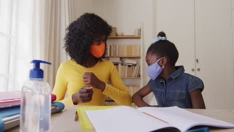 African-american-mother-and-daughter-in-home-wearing-face-masks