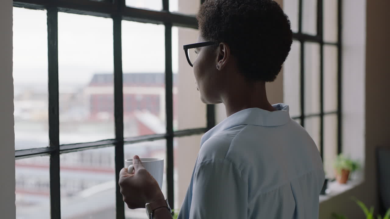 close up portrait african american woman drinking coffee at home black entrepreneur enjoying relaxed morning looking out window thinking contemplative wearing glasses