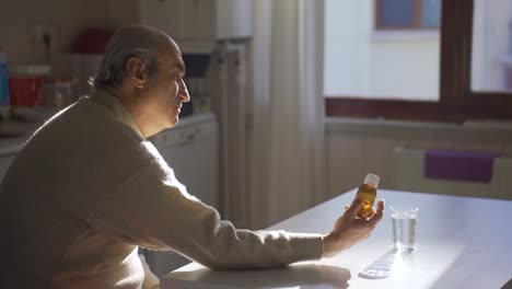 Anciano-Enfermo-Mirando-El-Frasco-De-Medicina-En-La-Cocina-De-Casa.