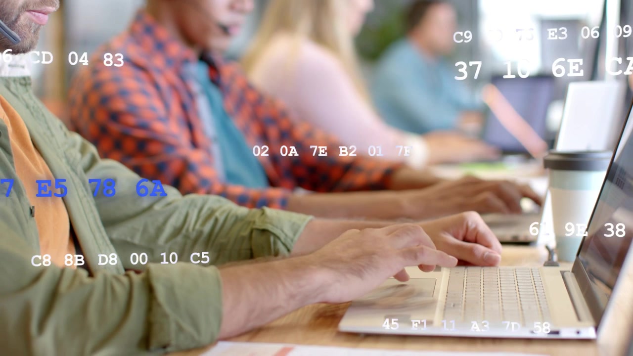 Team typing on laptops at desk, camera shifting ahead while hex data overlay showing tech workflow