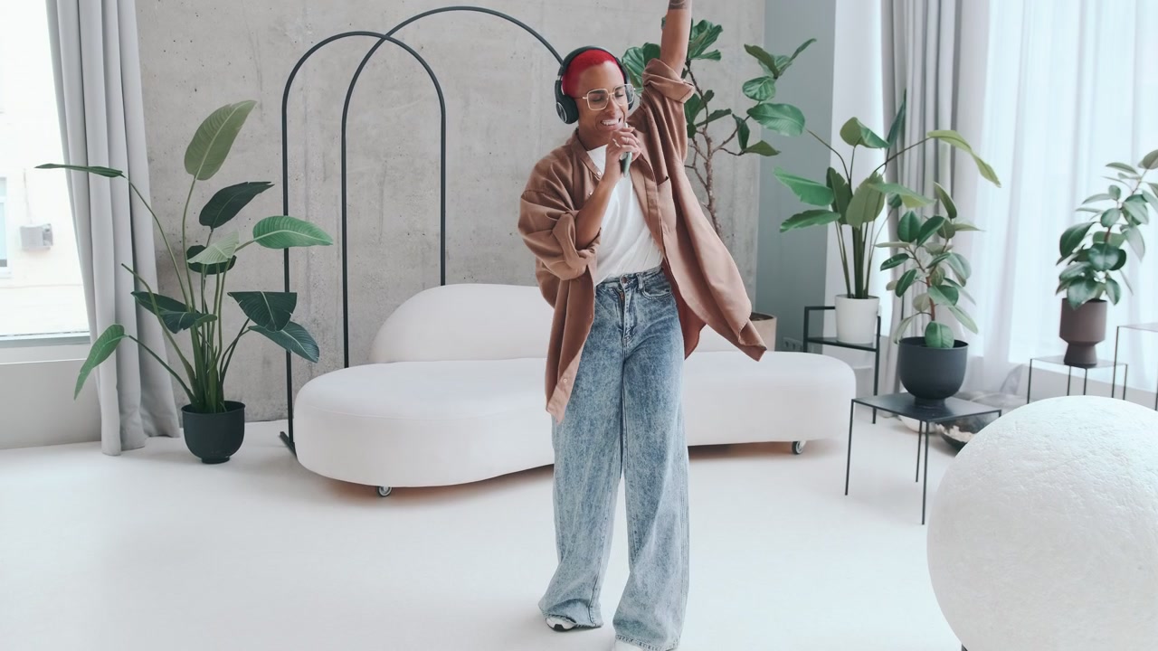 Young african american woman dancing using mobile phone instead of microphone