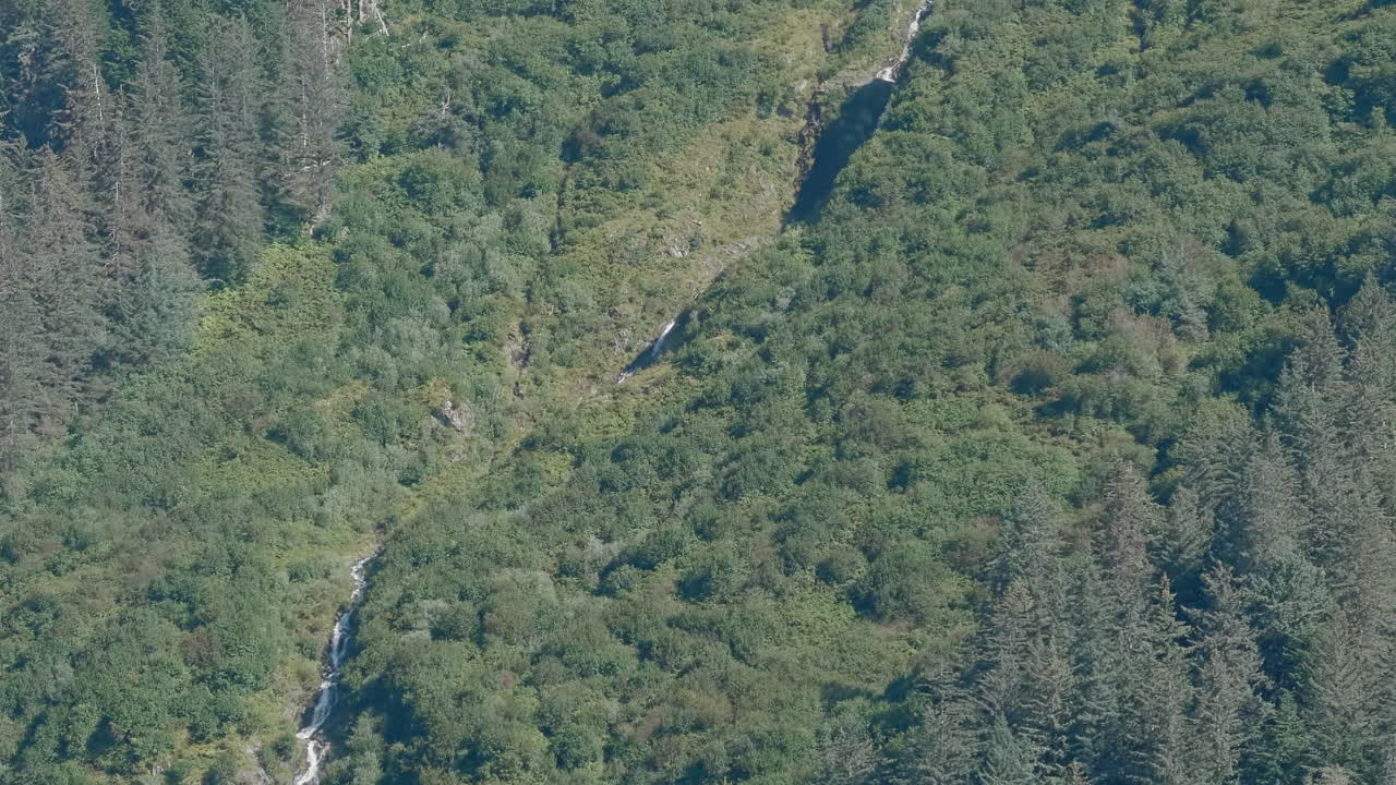 Tilt down of a waterfall in the mountainside near Juneau, Alaska.