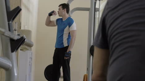 man drinking water during break in the gym