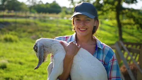 woman holding a baby goat on a farm