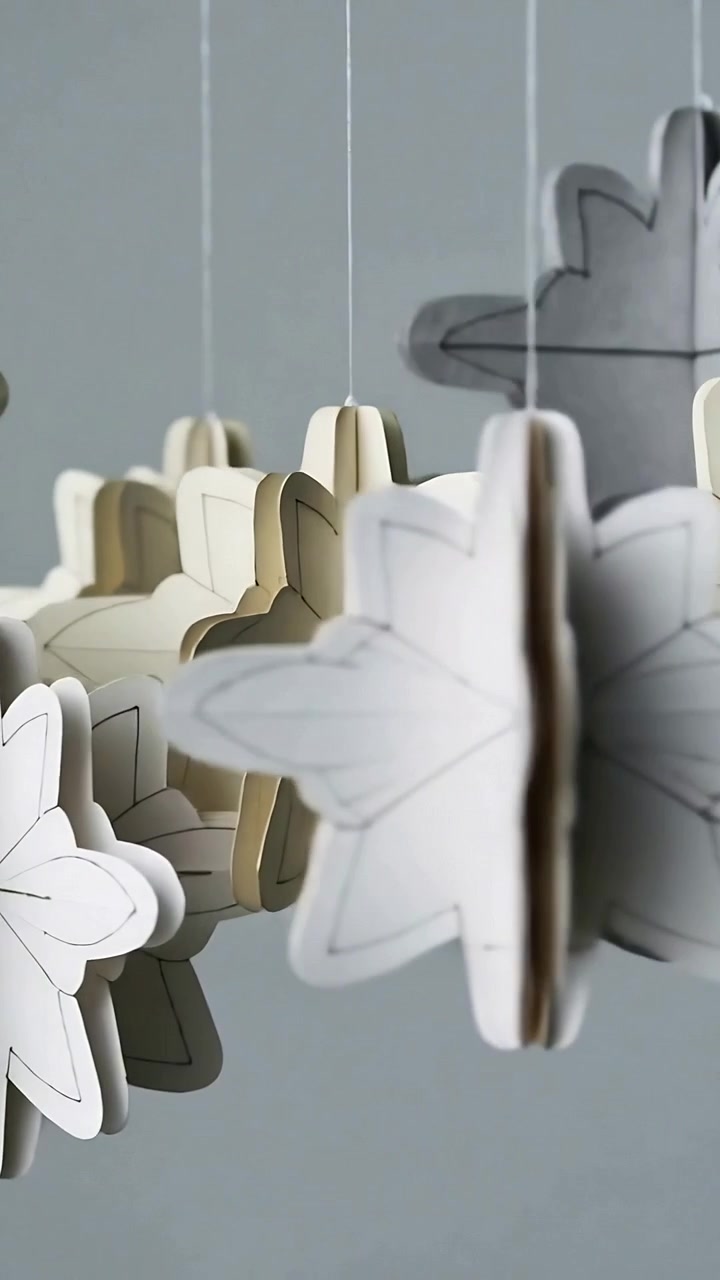Vertical video: Shifting camera revealing hanging paper flowers in studio, to reveal layered petals
