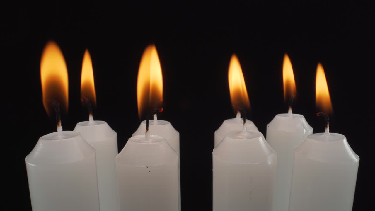 vista macro quemando velas blancas sobre fondo negro, noche silenciosa, memorial, tiro estático de 4k
