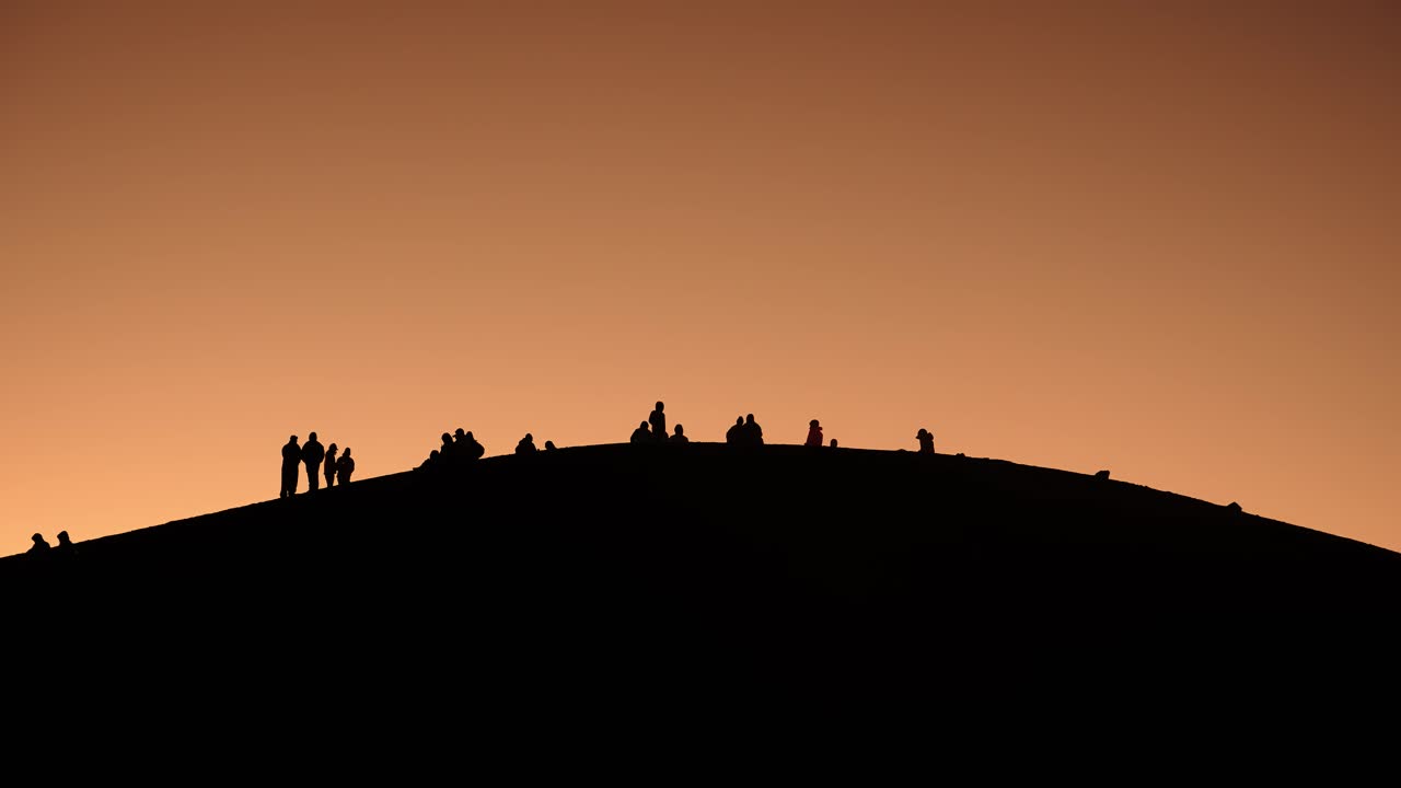 Silhouettes of hikers watching sunrise from the summit of Acatenango volcano in Guatemala