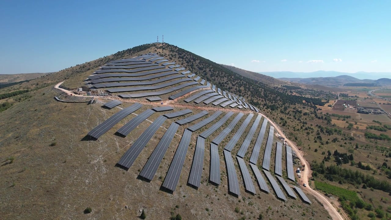 Solcellepark på bjergskråning i Kozani, Grækenland. Solpaneler opfanger sollys for at producere vedvarende energi ved hjælp af fotovoltaiske celler, bredt luftfoto