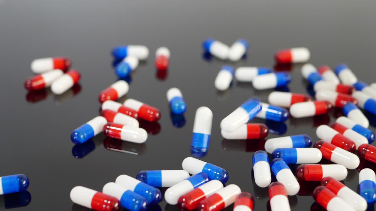 마약 알약과 진통제 약 캡슐이 떨어지고 검은색 외진 배경에서 느린 동작으로 튀는