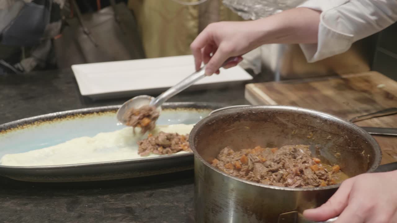 요리사는 으깬 감자와 구운 고기로 접시를 도금합니다