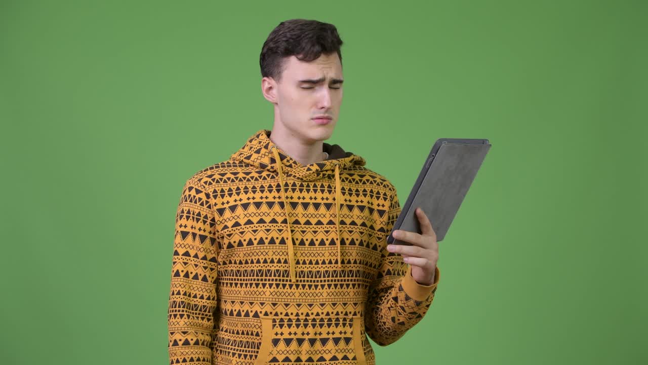 Young handsome man using digital tablet and getting bad news