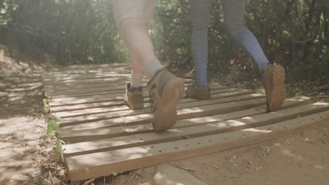 low section of african american couple hiking on boardwalk in forest, slow motion