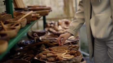 tourist woman shopping at city street bazaar, looking wooden handcraft items