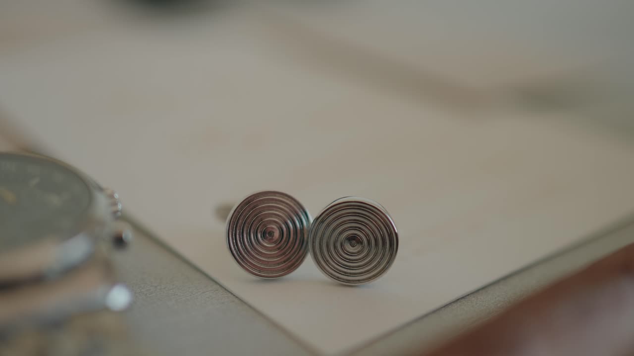 detailed shot of silver spiral cufflinks beside wristwatch symbolizing groom wedding elegance