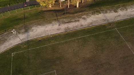 aerial top down view of only person running training at sunset in a football court