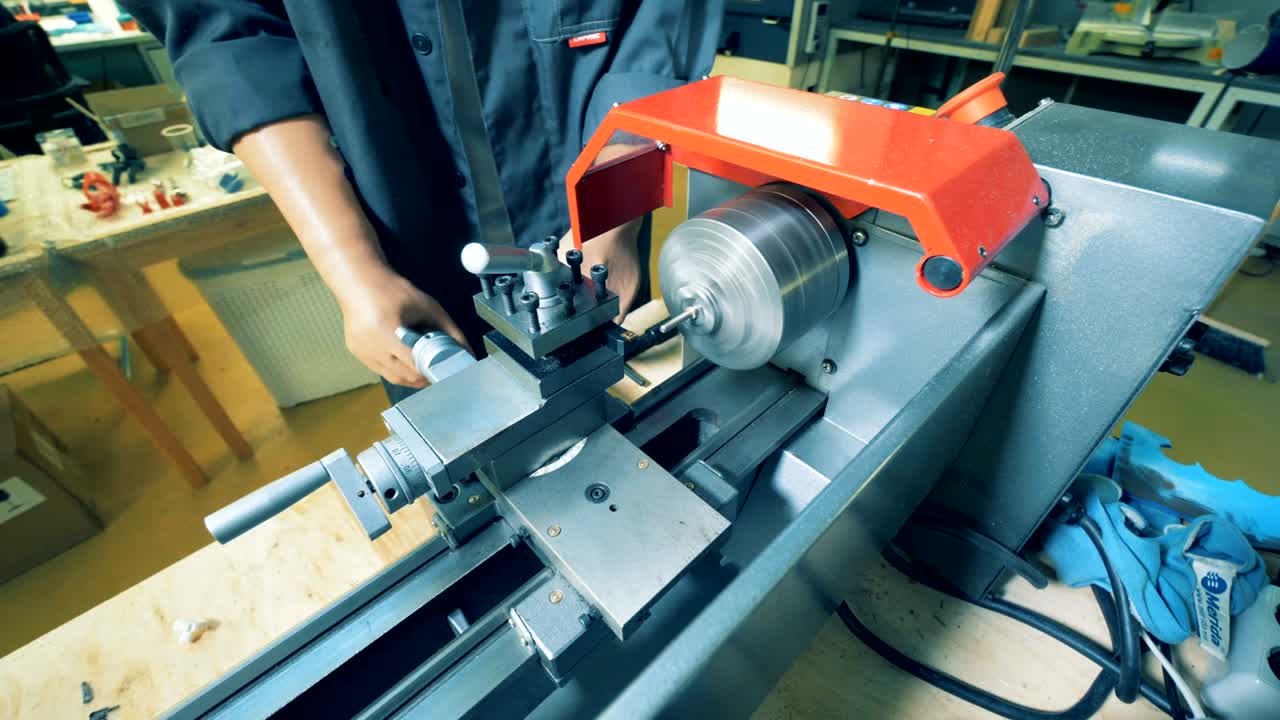 인공 손을 가진 남자가 공장 장비에서 금속 회전기를 사용하고 있습니다.