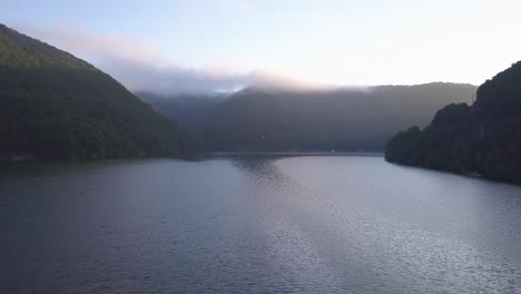 soft light of early morning shines on shimmering lake surface