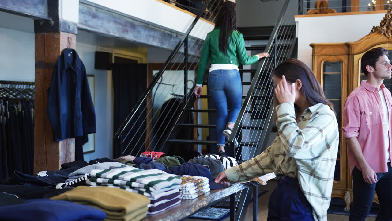 Interior Of Busy Fashion Store With Customers Browsing Clothes On Display