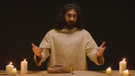 fotografía de estudio de un hombre vestido con túnicas, cabello largo y barba que representa la figura de jesucristo predicando