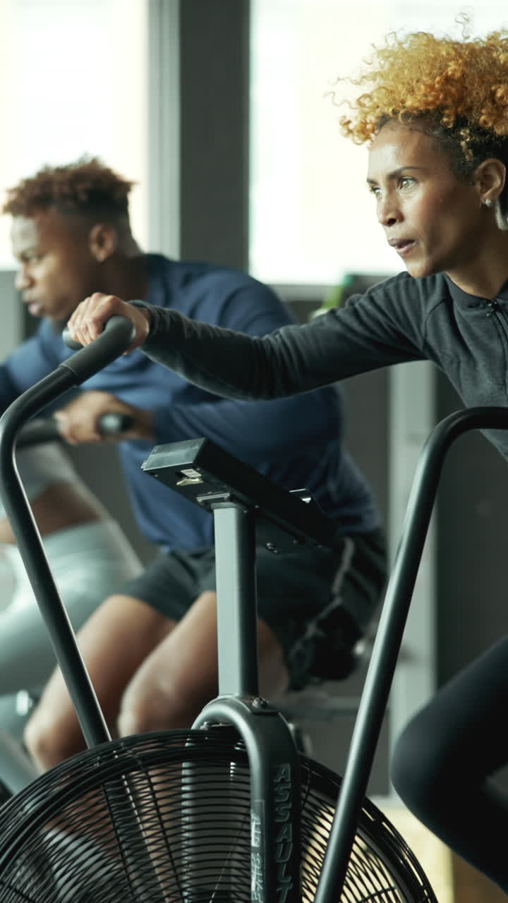 Determined Woman Exercising on Stationary Air Bike in a Modern Gym