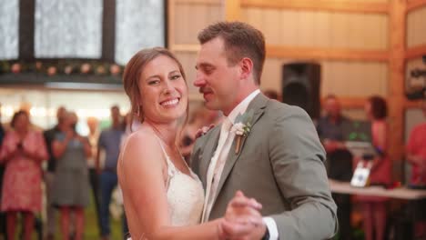 bride and groom share a joyful first dance, with the bride playfully winking