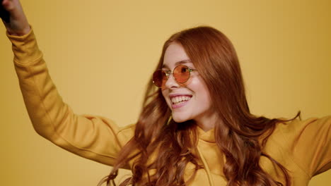 Happy-girl-dancing-with-smartphone-indoors.-Redhead-woman-listening-music