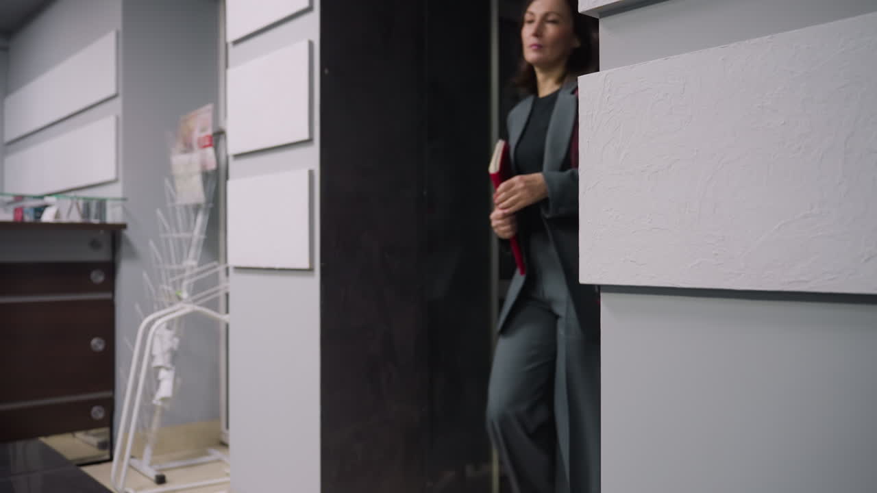 Interior of modern office with stylish design. Features office desk, white wall panels, magazine rack, and glass door with lion logo. Ideal for showcasing office space and professional environments