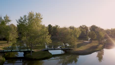 aerial pan of bridges over apollo park lake at golden hour in lancaster, california