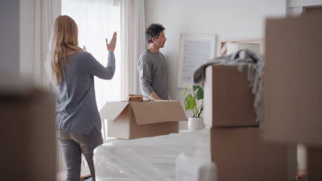 pareja feliz mudándose a una nueva casa colgando fotos en la pared decorando la casa disfrutando del trabajo en equipo 4k