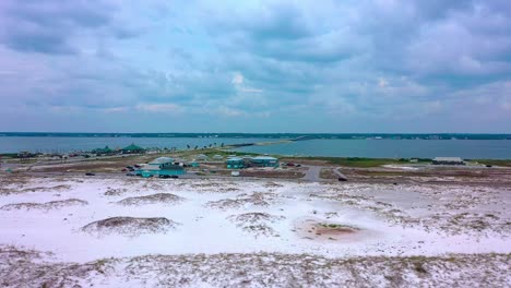 vista de drones volando sobre la arena blanca de la playa navarra fl mirando hacia las tranquilas aguas de la bahía de sonido con vistas al puente y al paseo marítimo