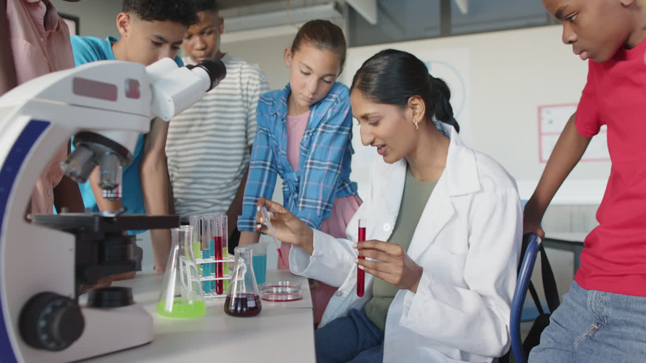 Demonstrating chemistry experiment, teacher in school with students, test tubes, and microscope