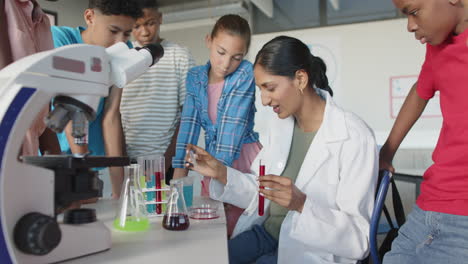 demonstrating chemistry experiment, teacher in school with students, test tubes, and microscope