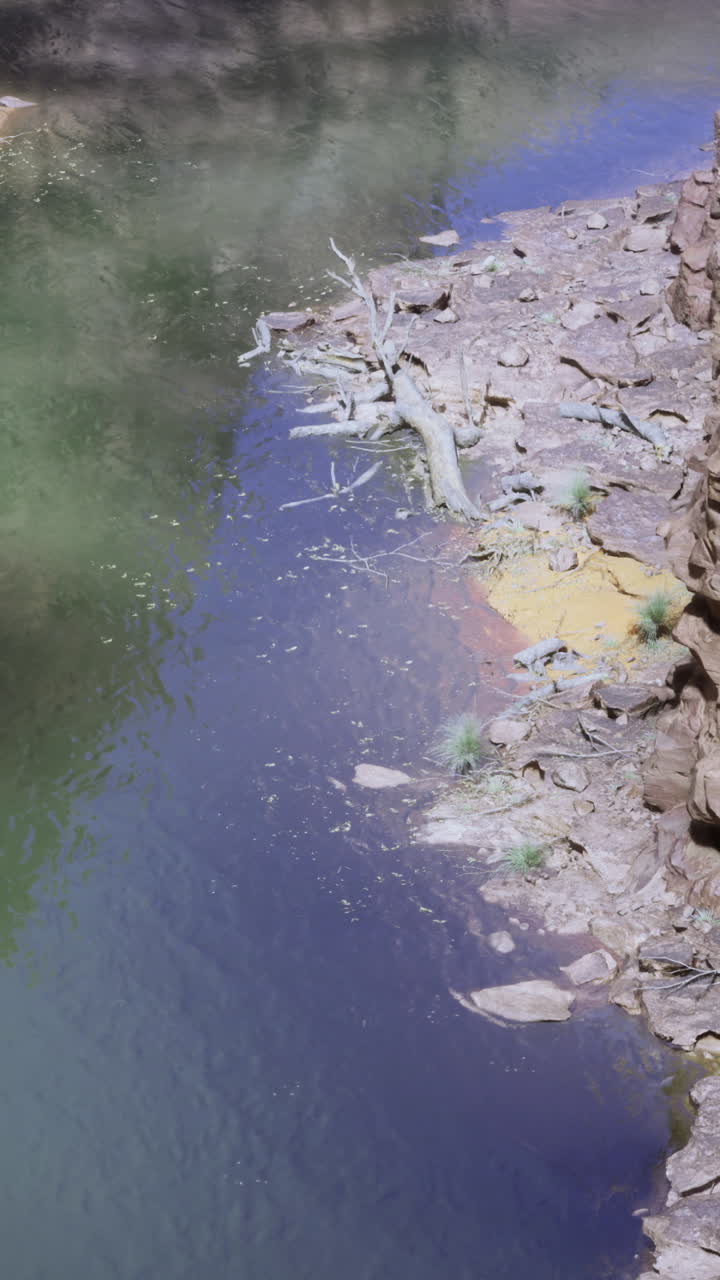 Rugged natural landscape with river beneath steep rock formations in sunlight