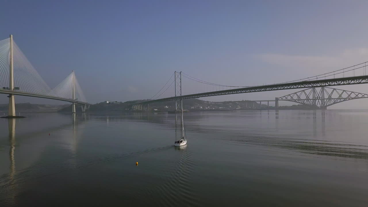 스코틀랜드 서부 lothian에서 화창한 날 south queensferry의 네 번째 다리 사이를 여행하는 범선의 항공 영상