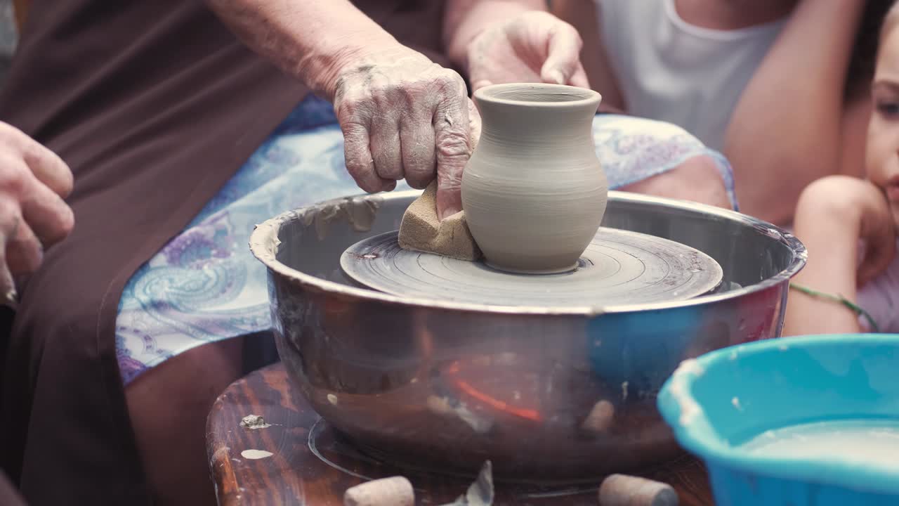 La nonna con i nipoti produce brocche in ceramica