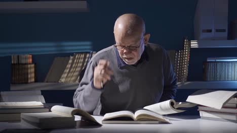 close-up shot of senior old man in glasses holding and reading an old book.