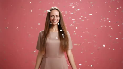 happy woman celebrating with confetti on a pink background