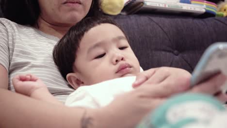 asian baby using smartphones with mom on the bed