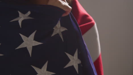 close up studio portrait shot of woman wrapped in american flag celebrating 4th july independence day