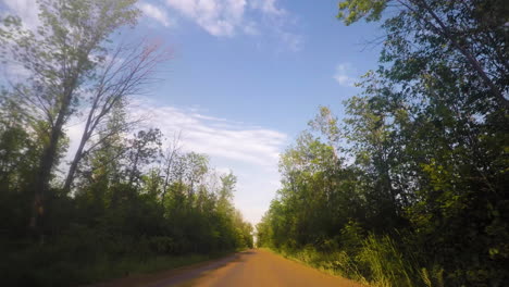 Car-driving-on-a-dirt-road-through-a-forest-during-sunset