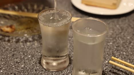 liquid being poured into a glass with ice cubes.