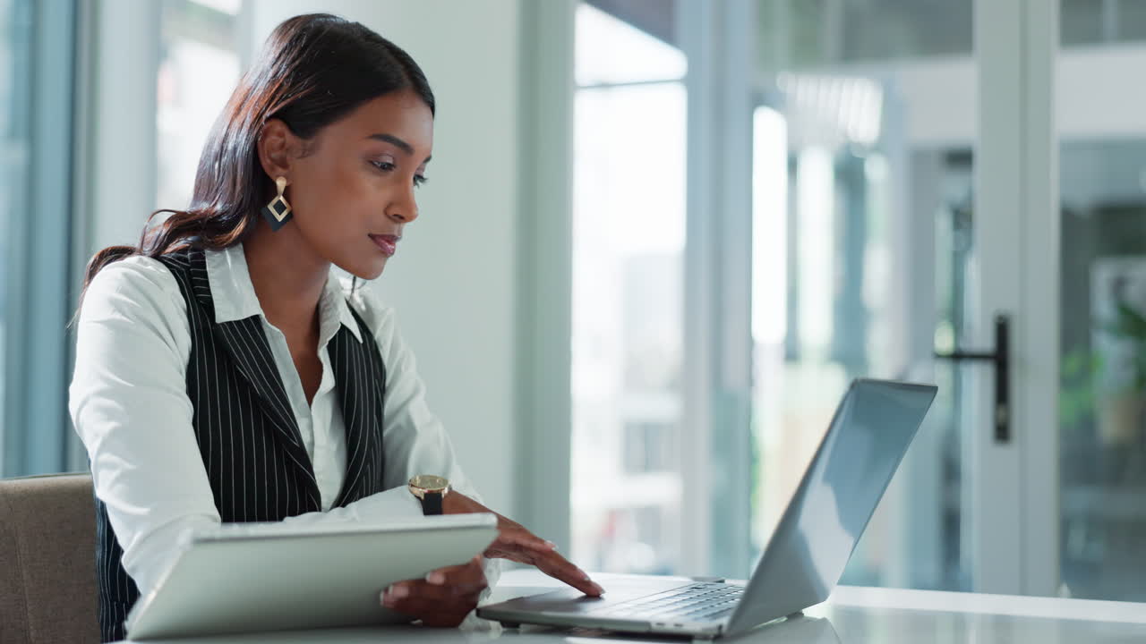 Businesswoman working on laptop and tablet in office