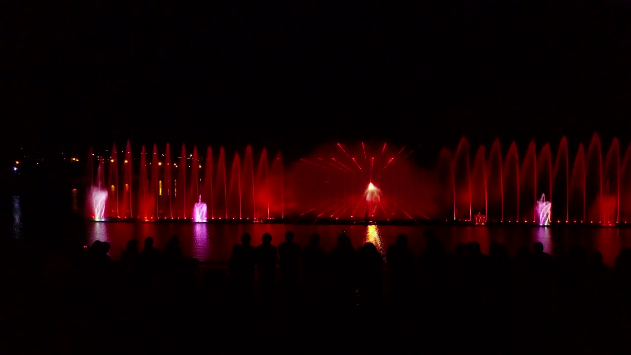 Fountain With Colorful Illuminations At Night. Aerial shot of the magic fountain - lights,colors and music spectacle at night