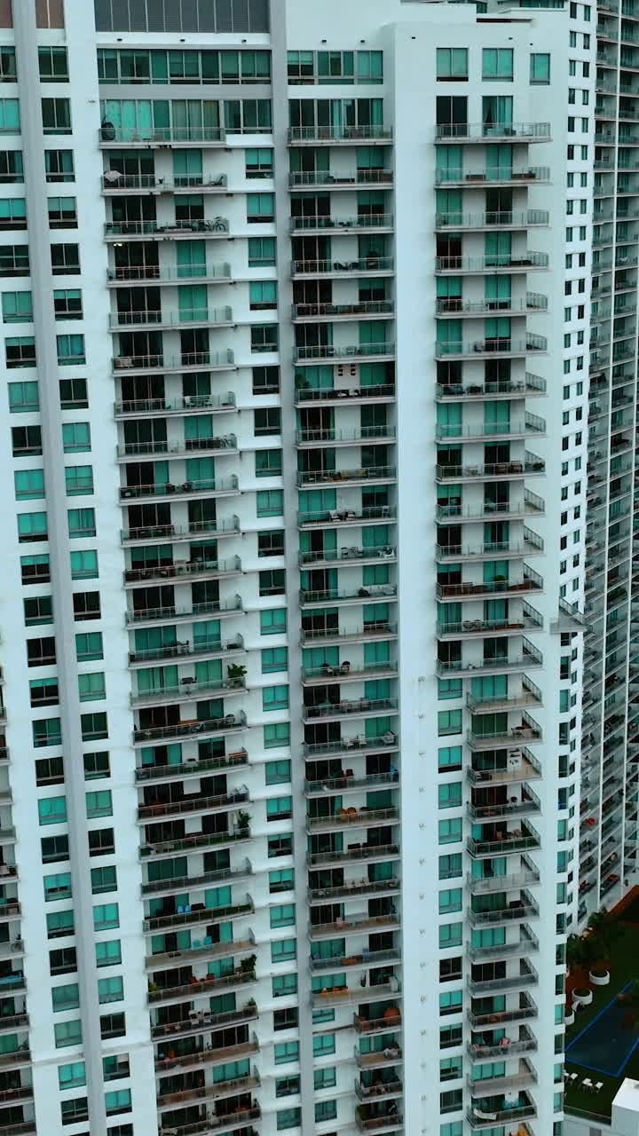 Multi-apartment high-rise building in the residential area. Miami downtown block of flats from top view. Vertical video