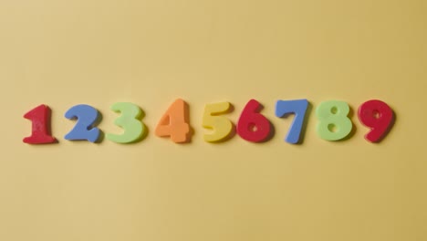 Studio-Overhead-Shot-Of-Plastic-Numbers-Arranged-In-Order-On-Yellow-Background-1