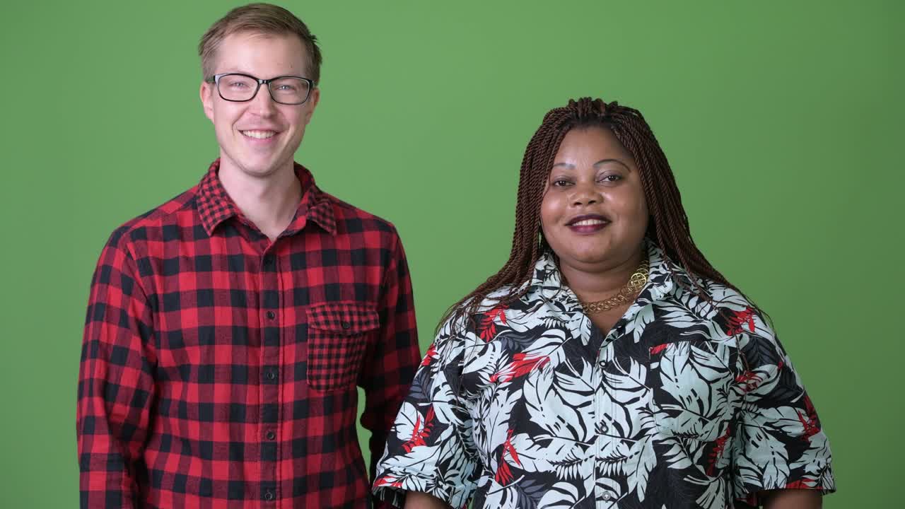 Afrikaanse vrouw met overgewicht en jonge Scandinavische man samen tegen een groene achtergrond.