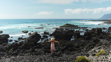 Joven-Hermosa-Mujer-Disfruta-De-Las-Rocas-Costeras-De-La-Isla-De-Tenerife,-Vista-Posterior