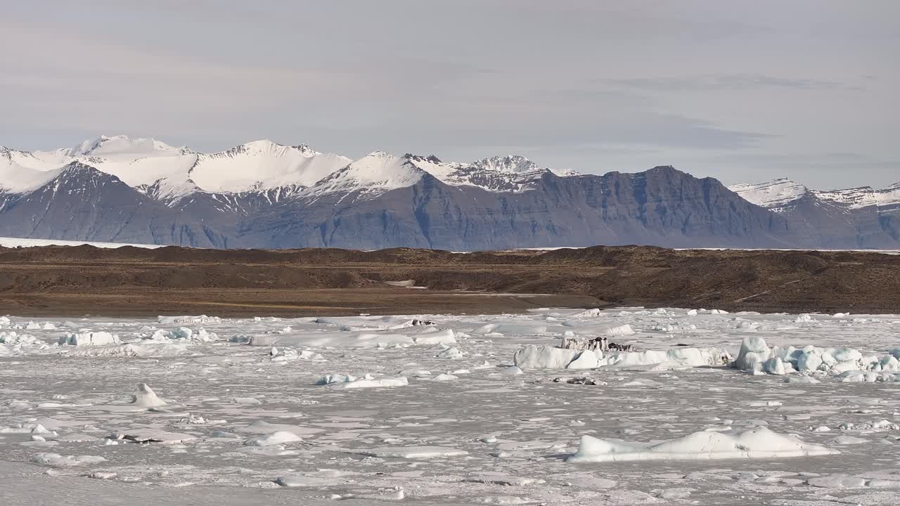 Icy Fjallsárlón lagoon stretches beneath vast snowy mountains in Iceland’s south