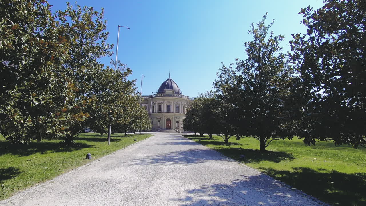 Approaching slowly the Ariana Museum in Geneva, in the central road, under a clear blue sky, with ray of suns.