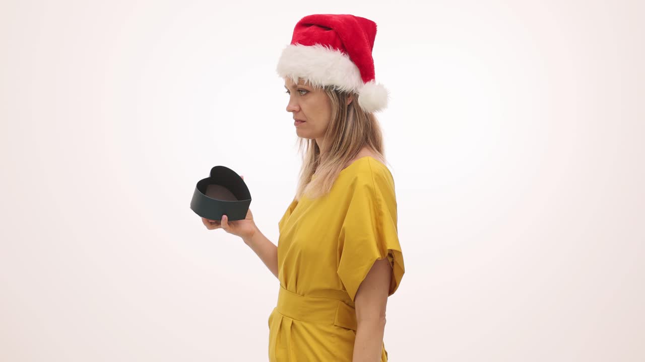 Woman in Santa Hat Looks Disappointed with Empty Heart-Shaped Gift Box